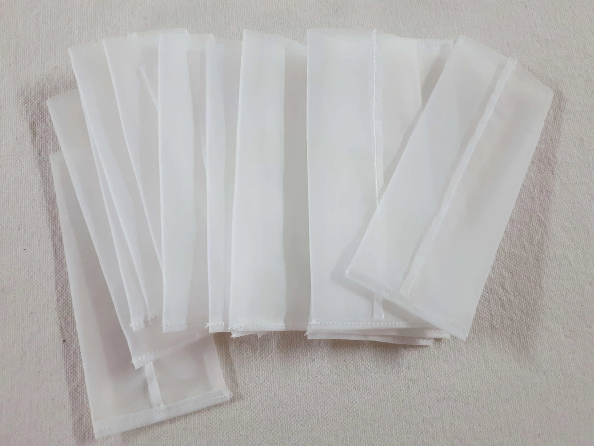 A collection of white rectangular mesh bags for rosin pressing.