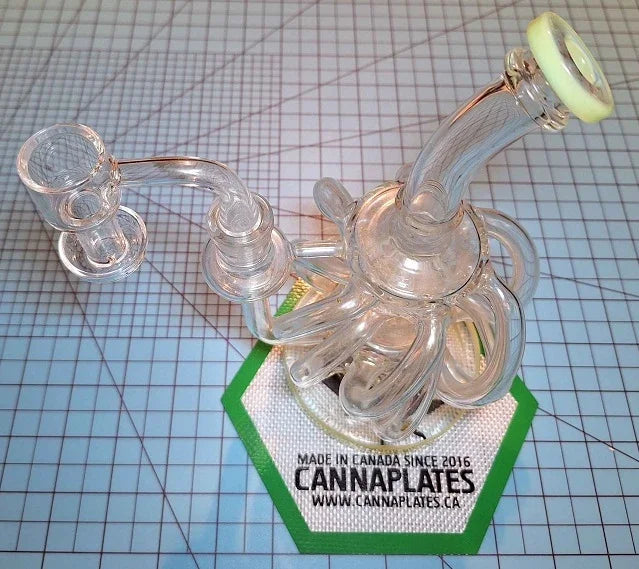 Intricate glass rig sitting on a CannaPlates branded hexagonal accessory mat.
