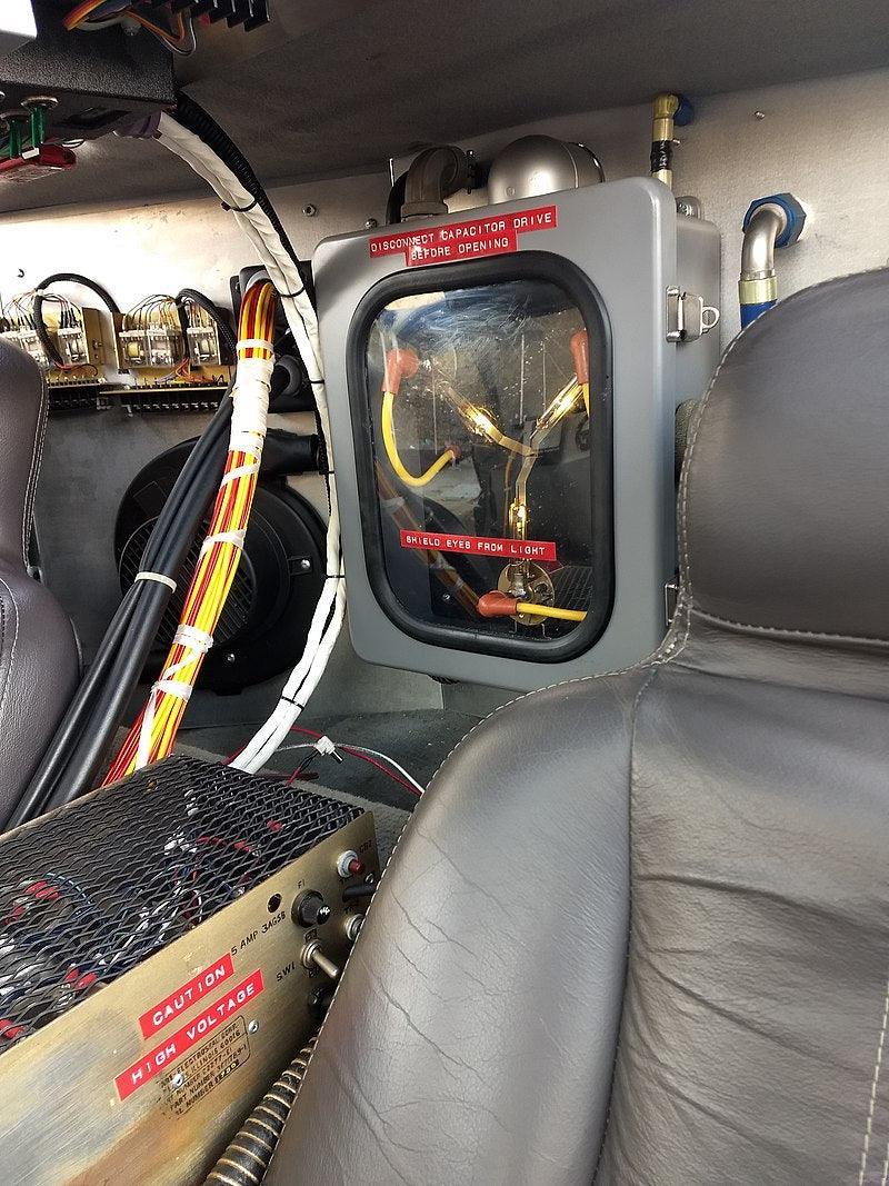 Close-up view of a high voltage electrical component with warning labels inside a machine.