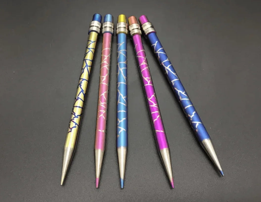 Five colorful laser-engraved metallic pens with geometric patterns on a black background.