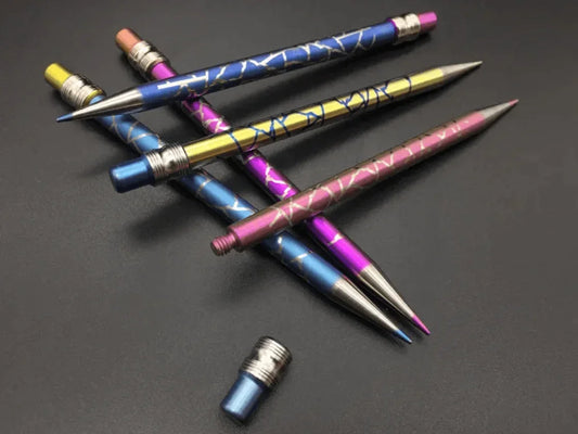 Assorted colorful metal dabber tools with geometric patterns on a dark background.